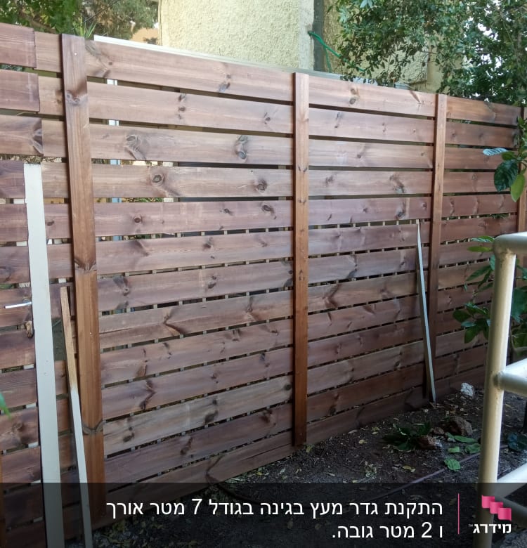 גדר עץ חומה עם צמחים מסביב